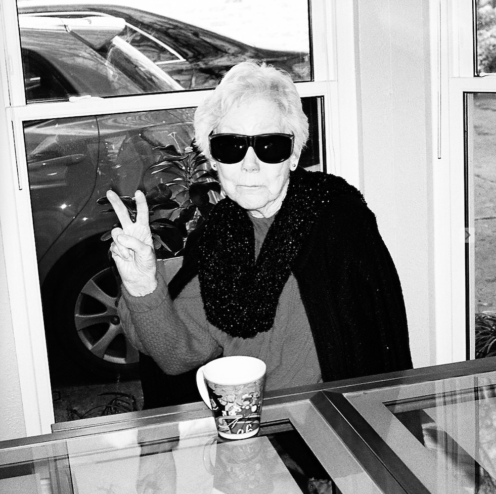 An older woman smiling and giving a peace sign
